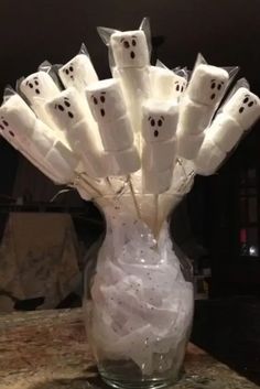 a glass vase filled with white marshmallows and ghost eyes on it's sides