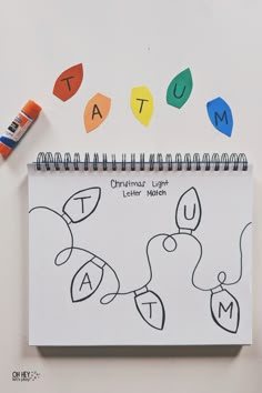 a spiral notebook with the word autumn written on it and colored crayons next to it