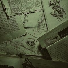 some drawings are on top of an open book with eyeglasses and books in the background