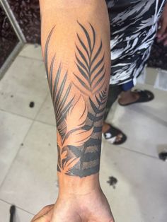 a person with a palm leaf tattoo on their arm, holding up his hand to the camera