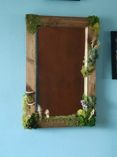 a wooden frame with moss growing on it and two framed pictures hanging on the wall