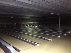 there are many bowling lanes lined up in the room with their lights on and one is empty