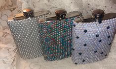 three silver and blue flasks are sitting on a white cloth