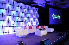 a stage set up for a conference with couches and chairs in front of it