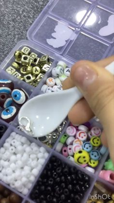 a person is holding a spoon in a container filled with buttons and bead parts