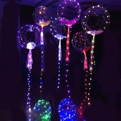 lighted balloons and streamers in the shape of balls are hanging from a ceiling at night