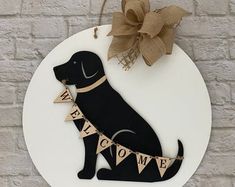 a welcome sign with a black dog on it and a burluck bow hanging from the front