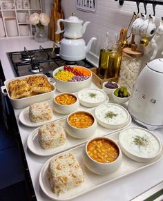 a kitchen counter topped with lots of bowls and plates filled with different types of food