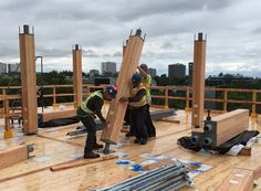 two men working on the roof of a building with wooden beams in front of them