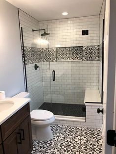 a bathroom with black and white tiles on the floor, shower stall, toilet and sink