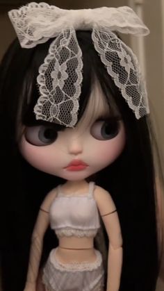 a close up of a doll with long black hair and lace on it's head