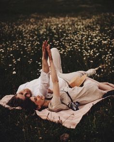 a woman laying on top of a blanket in a field