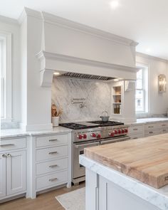 a kitchen with marble counter tops and white cabinets, along with an island in the middle