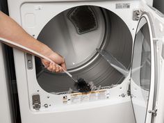 a person is using a brush to clean the front of a washing machine with it's door open