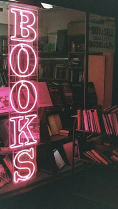 there is a neon sign that says books in front of the bookcases and shelves