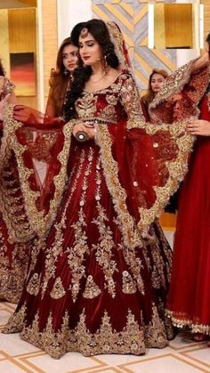 three women in red and gold wedding dresses posing for the camera with their arms around each other