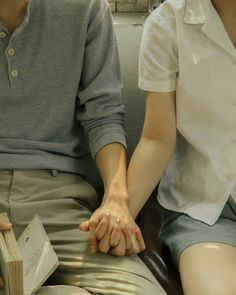 two people sitting on a couch holding hands