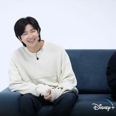 a man sitting on top of a blue couch next to a person wearing a white sweater