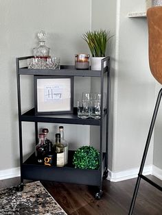 a shelf with liquor bottles and glasses on it next to a bar stool in a living room