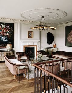 a living room filled with lots of furniture and paintings on the wall next to a fire place