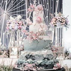 a wedding cake with pink flowers on the top is surrounded by other floral arrangements and decorations