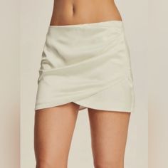 This Ten By Babaton Skirt In Soft Ivory Features A Faux Wrap Style With A Flattering Straight And Pencil Design. The Skirt Is Accented With A Zipper For Added Style. The Size 2 Skirt Has Side Rushing And Is Brand New Without Tags. Originally Priced At $149, This Skirt Is Perfect For Any Occasion And Can Be Dressed Up Or Down. Please Note The First Picture On The Listing Is A Stock Photo The Actual Skirt You Will Receive Is Shown On The Rest Of The Photos Length 17 1/2 Inches Waist 12 Inches Cream Fitted Mini Bottoms, White Asymmetrical Lined Skort, Fitted Cream Mini Bottoms, Summer Night Out Skirt With Side Zipper, White Asymmetrical Pleated Mini Skirt, Chic White Fitted Skort, Spring Party Skirt With Side Zipper, Elegant Beige Party Skort, Fitted Cream Asymmetrical Skirt