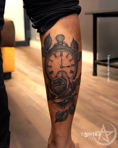 a person with a tattoo on their leg has a clock and rose tattooed on it