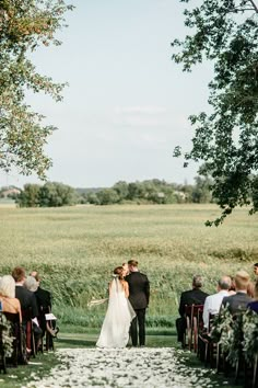 the bride and groom are walking down the aisle at their wedding ceremony in an open field