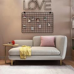 a gray couch sitting in front of a wall with pictures on it and a lamp