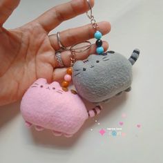 a person is holding two small stuffed animals in their hands, one has a keychain and the other has a ring