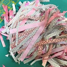 a pile of pink and grey ribbon on top of a green table next to scissors