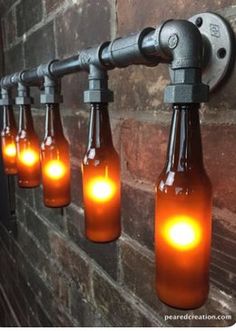 there are six bottles with lights in them hanging on the wall next to a brick wall