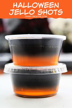 halloween jello shots in plastic cups with orange and black liquid on the top, sitting on a table