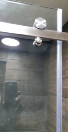 a person taking a selfie in a shower with a mirror above the glass door