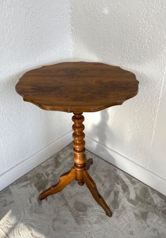 a small wooden table sitting on top of a carpeted floor next to a white wall