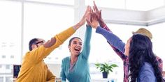 group of people raising their hands in the air at an office meeting or social gathering