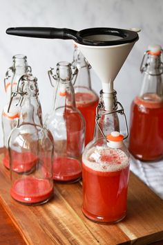 several glass bottles filled with liquid on top of a wooden table