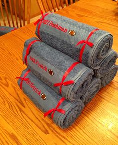 three towels wrapped in red ribbon sitting on top of a wooden table