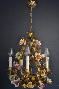 a chandelier with flowers and candles hanging from it