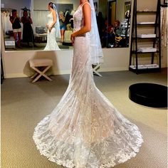 a woman standing in front of a mirror wearing a wedding dress