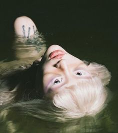 a woman is floating in the water with her head above the water's surface