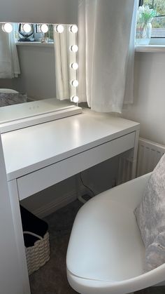 a white vanity with lights on it and a chair