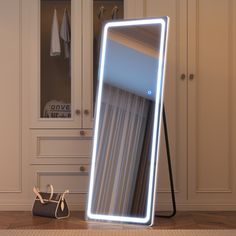 a large mirror sitting on top of a wooden floor next to a purse and coat rack