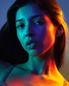 a woman with bright lights on her face and chest, posing for a photo in front of a blue background