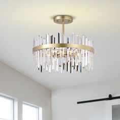 a chandelier hanging from the ceiling in a room with white walls and windows