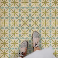 someone's feet in sandals standing on a patterned wallpaper floor with geometric designs