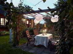 an outdoor dining area with table, chairs and lanterns on the patio at night time