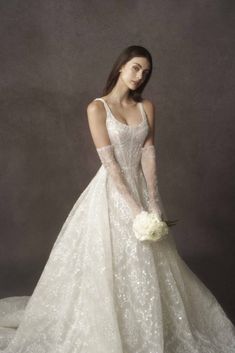 a woman in a wedding dress with gloves on her hand and holding a flower bouquet