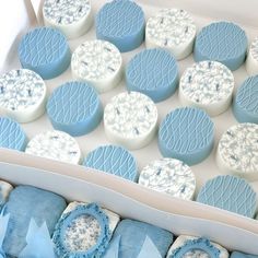 a box filled with blue and white cookies next to some frosting on top of each other