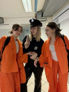 three women in orange prison uniforms standing next to each other